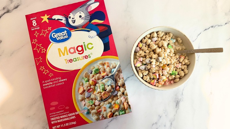 Box of Great Value Magic Treasures cereal next to bowl of cereal with spoon on marble surface
