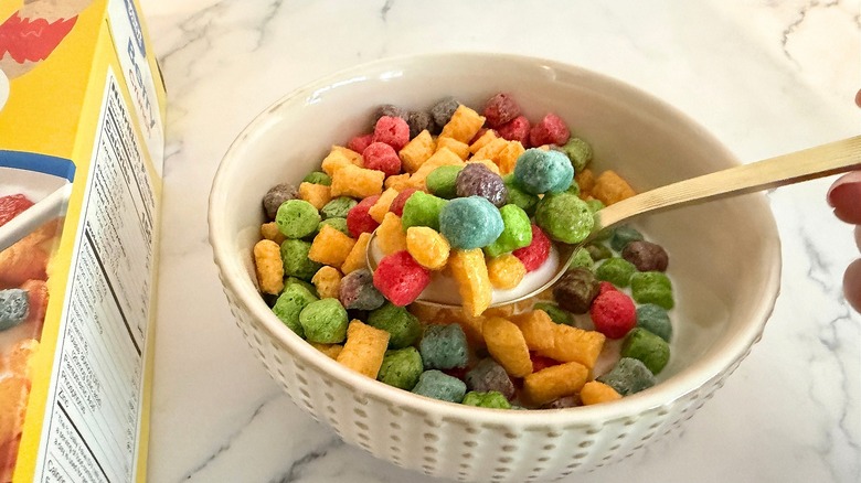 Hand holding spoon of cereal above cereal bowl
