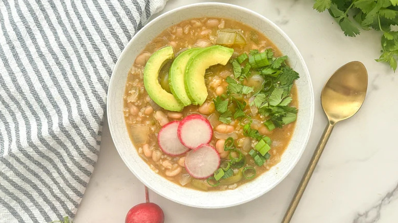 tomatillo and white bean chili in bowl with avocado