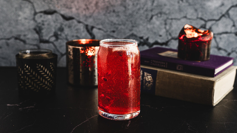 Red cocktail in glass with dark Halloween-themed background