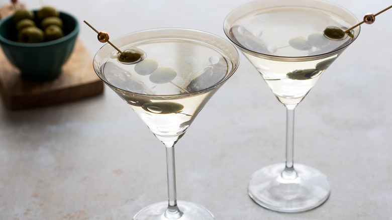 Two dirty martini cocktails garnished with green olives