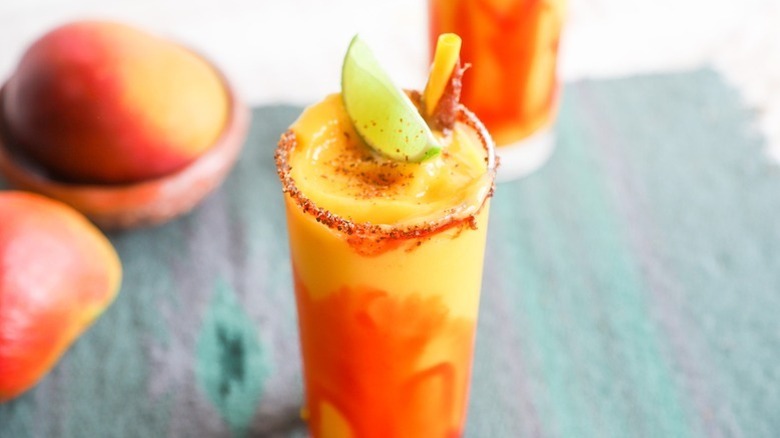 Mango cocktail in glass with Tajín rim, garnished with lime wedge