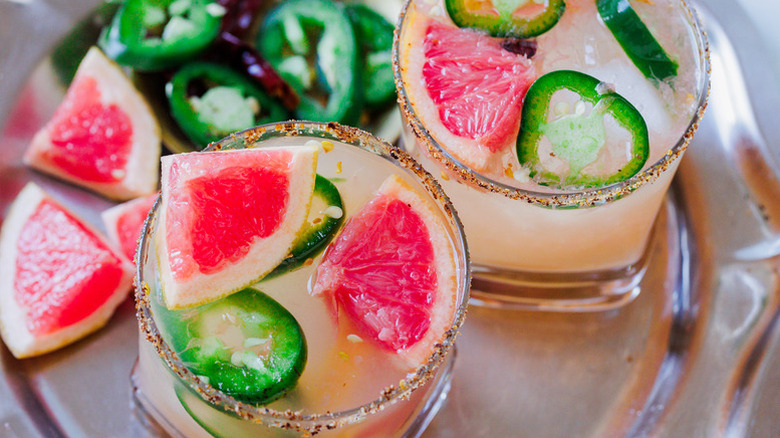 Two spicy margarita cocktails garnished with grapefruit wedges and jalapeno slices