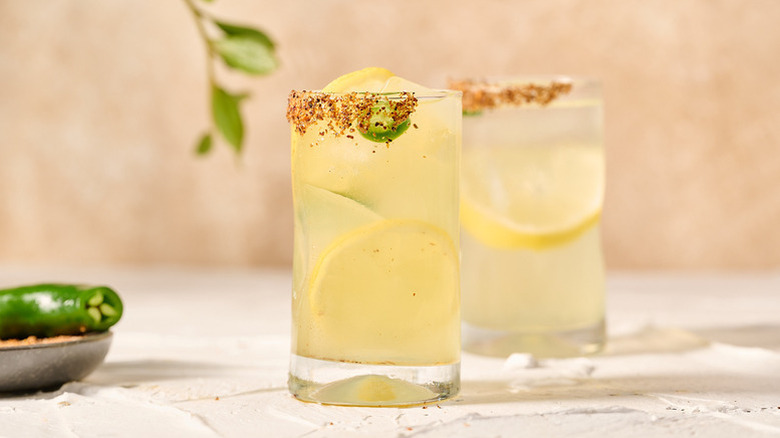 Pineapple lemonade cocktails in glasses, with lemon rounds and jalapeno slices