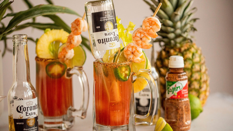 Michelada cocktail in glass, garnished with shrimp, lime, and upside-down Coronita beer bottle
