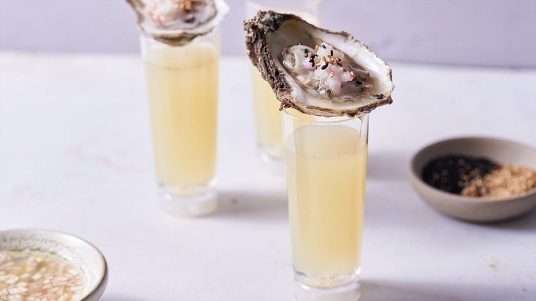 Yuzu shooter cocktails in glasses, topped with fresh oysters