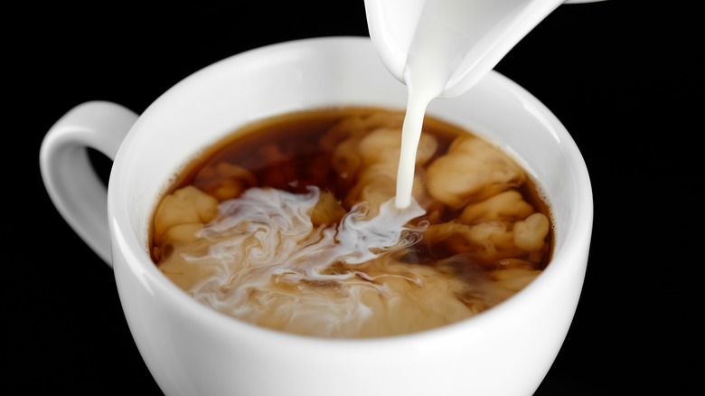 Pouring coffee creamer into cup