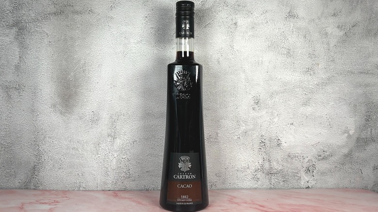 Bottle of Joseph Cartron Cacao Liqueur on grey wall background
