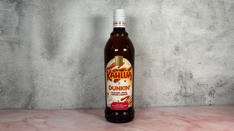 Bottle of Kahlua x Dunkin' Caramel Liqueur on grey wall background