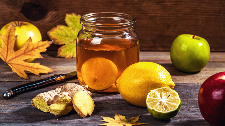 Switchel in a mason jar surrounded by fruits and ginger