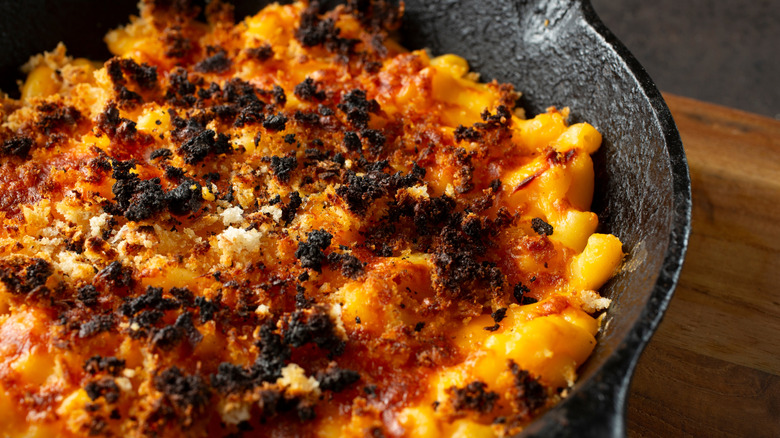 A close-up of rustic mac and cheese with charred cheese bits on top in a cast iron skillet
