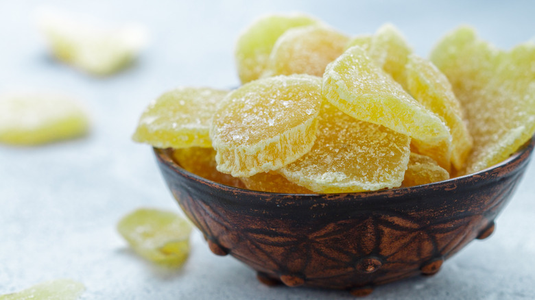 Candied ginger slices in a bowl on a light blue background