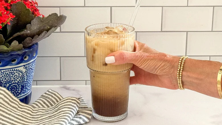A person holding a copycat Starbucks Brown Sugar Oatmilk Shaken Espresso in a glass