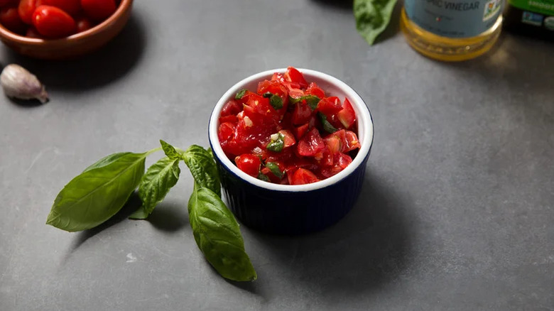 Copycat Trader Joe's Bruschetta Sauce served in a bowl with fresh basil on the side