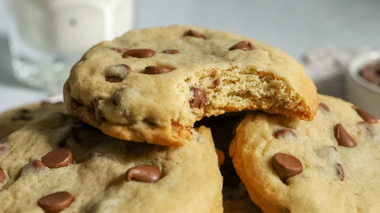 Crumbl Chocolate Chip Cookie with a piece missing with more cookies underneath