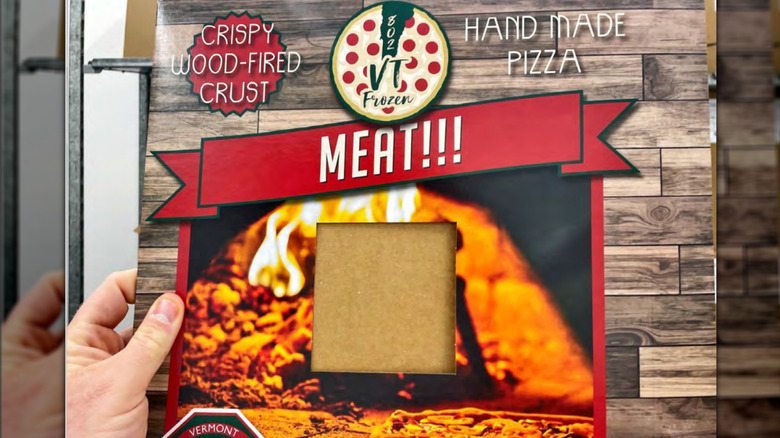 hand holding up a boxed frozen meat pizza from 802 VT pizza company