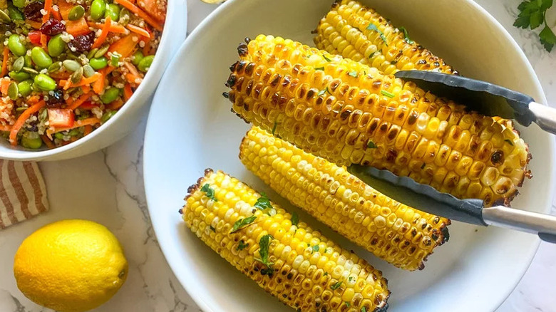 Easy Grilled Corn on the Cob and Garlic Butter in white bowl next to salad