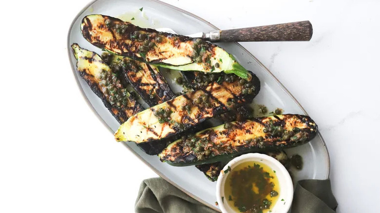 Grilled Zucchini with Caper Sauce on oblong white plate