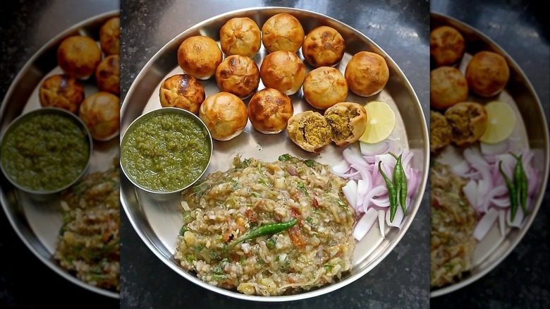 Wheat balls on plate alongside chutney, onions, lemon, and mashed vegetables