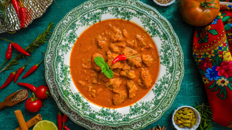 Overhead shot of pork vindaloo in bowl, surrounded by ingredients