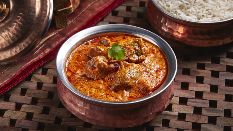 Lamb rogan josh served in copper pot alongside rice