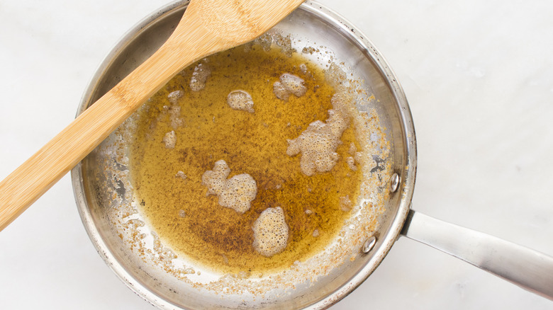 Brown butter in metal pan on white background