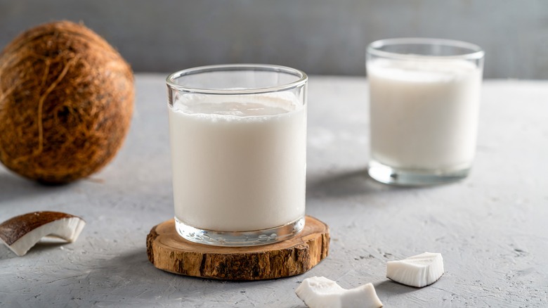 Coconut milk in glasses with a whole coconut in background