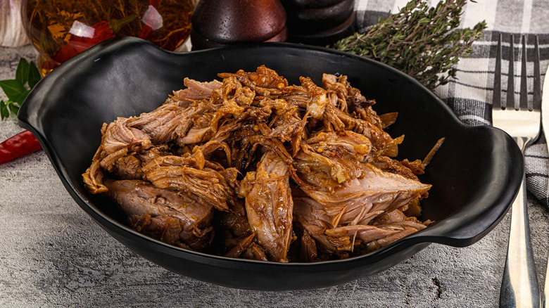 Cooked pulled pork in black serving bowl