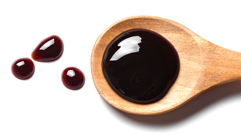 Soy sauce on wooden spoon on white background