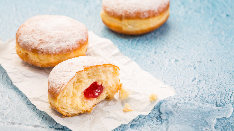Two Berliner, one sliced open to reveal berry jam inside