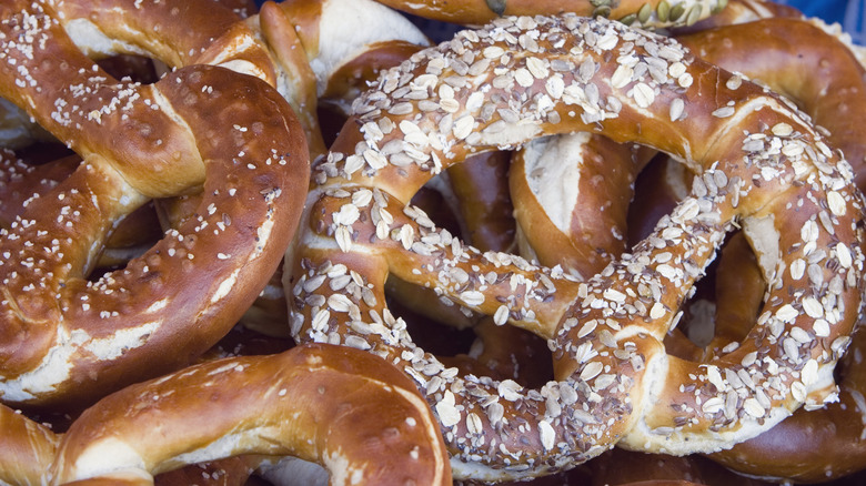 Various brezeln topped with salt, oats, and seeds