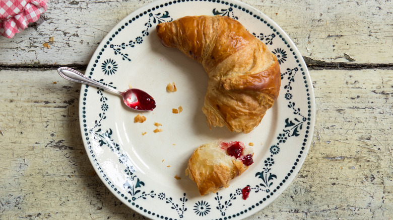 Croissant on plate with jam and spoon