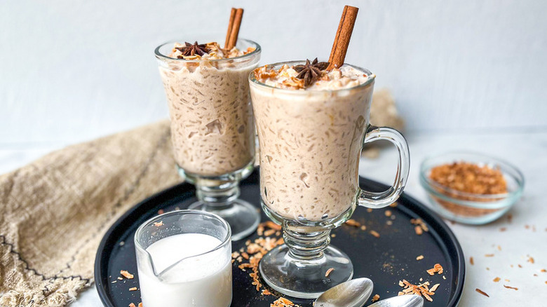 Coconut chai rice pudding in two tall serving glasses with cinnamon sticks and star anise
