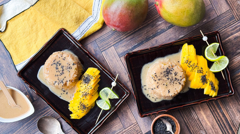 Two plates of mango sticky rice with lime twist garnishes