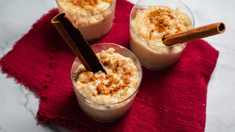 Spiced rice pudding in three serving glasses, with cinnamon sticks