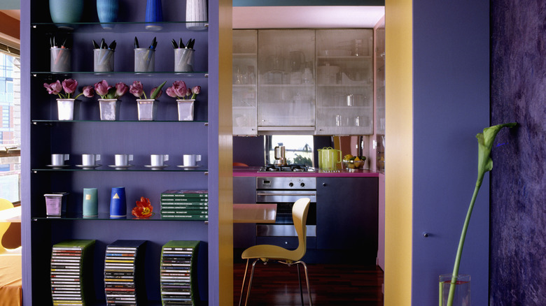 A kitchen doorway painted orange on the inside with purple walls on the outside.