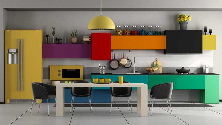 A kitchen with each cabinet and appliance painted a different color.