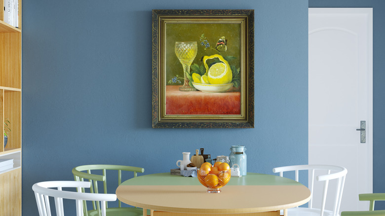A painting of a glass of lemonade next to a partially peeled lemon hanging above a kitchen table.