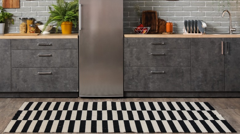 A black and white checkered rug in a kitchen.