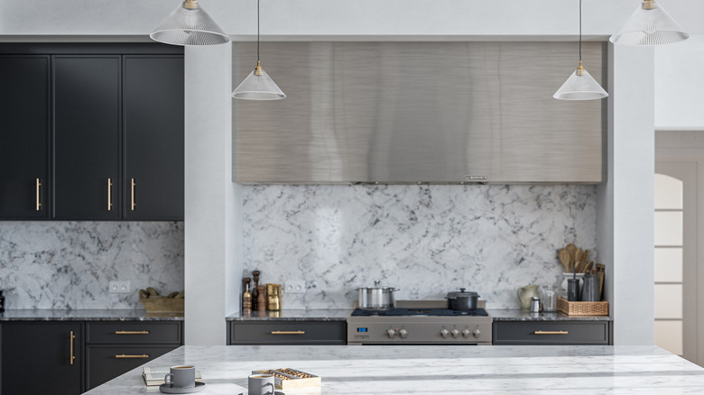 Kitchen with metal overhead above stove with metal handles on cabinets.