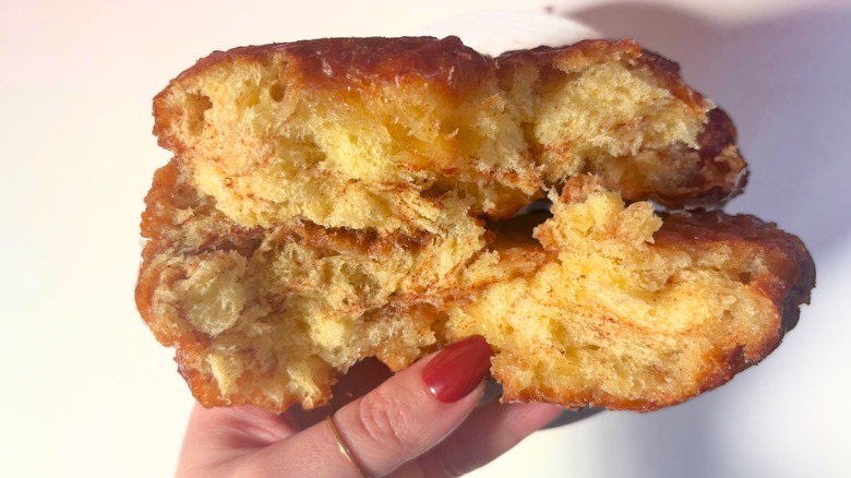 Hand holding split open apple fritter from Voodoo Doughnuts
