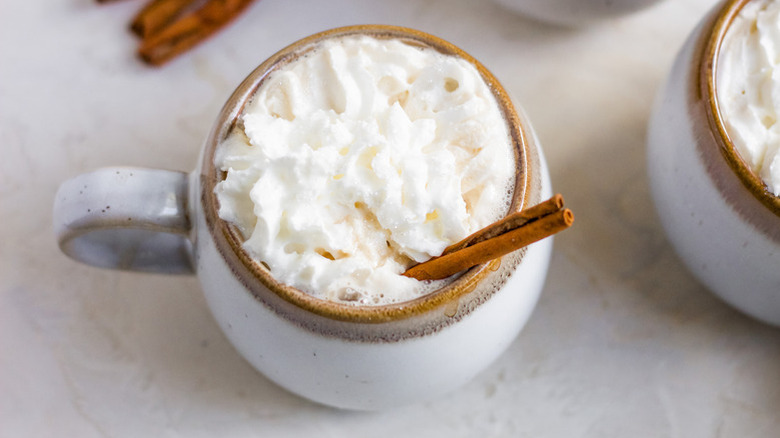 Cinnamon coffee in mug with whipped cream and cinnamon stick
