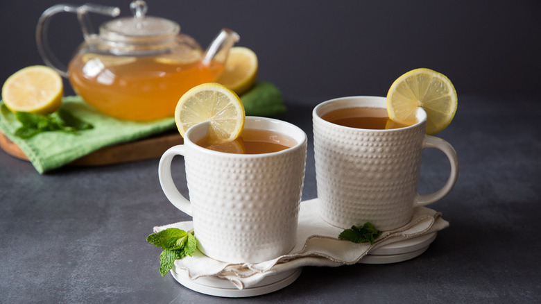 Two mugs of tea with lemon round garnishes