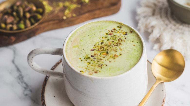 Pistachio latte in mug on saucer with spoon
