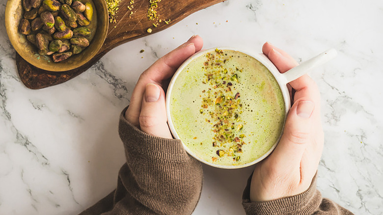 Hands holding mug of pistachio latte