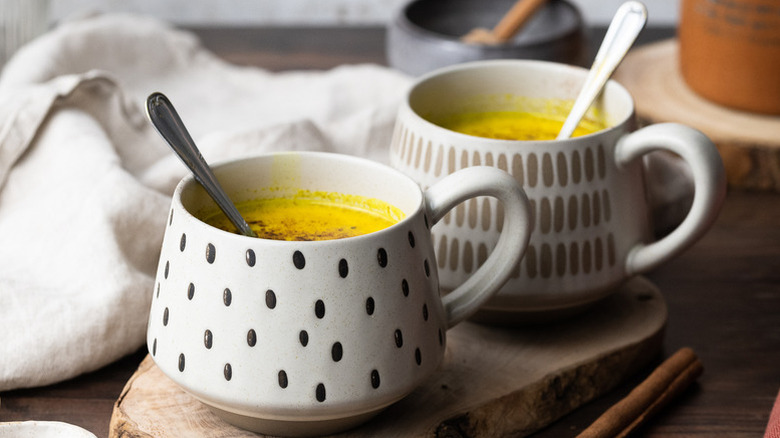 Two mugs of turmeric golden milk with spoons