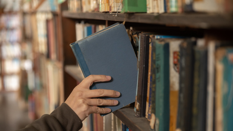 someone pulling book from shelf