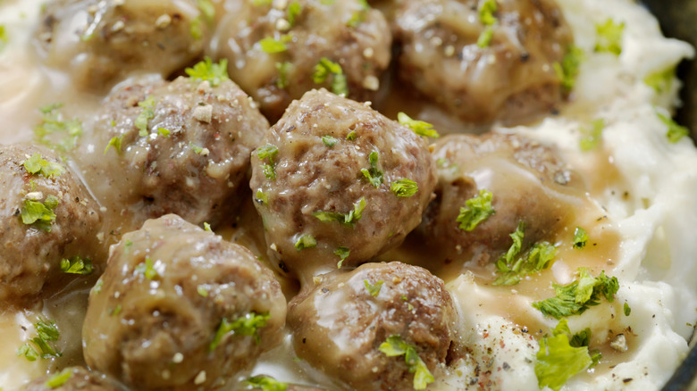 Close up of Swedish Meatballs with Mashed Potatoes garnished with fresh greens