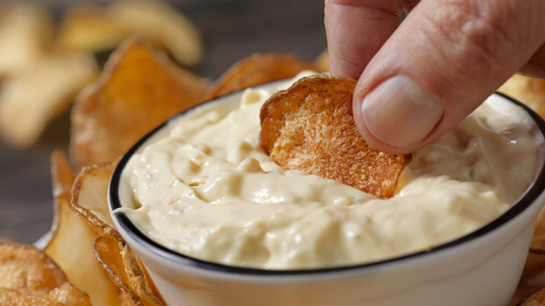 fingers dipping a potato chip into a bowl of California dip