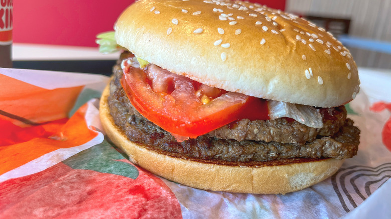 A Ddouble Whopper featuring two beef patties, lettuce, and tomato, on a sesame seed bun